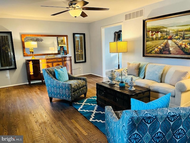 living area featuring baseboards, a ceiling fan, visible vents, and wood finished floors