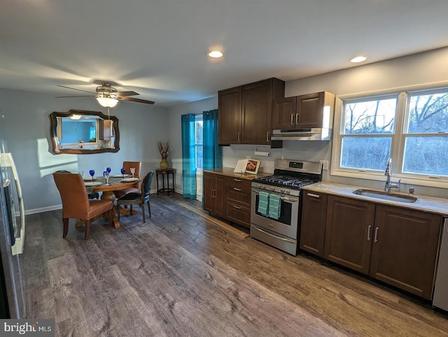 kitchen with under cabinet range hood, a sink, dark brown cabinetry, light countertops, and appliances with stainless steel finishes