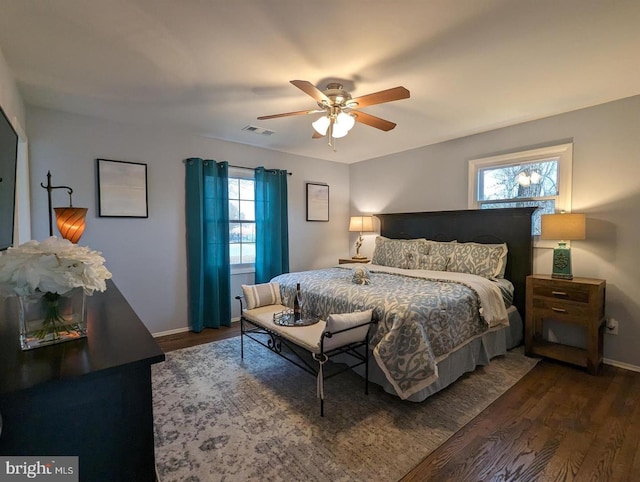 bedroom with a ceiling fan, visible vents, wood finished floors, and baseboards