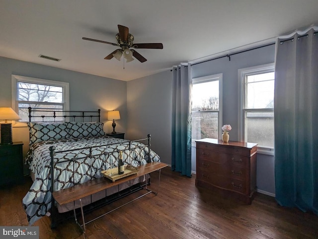 bedroom featuring wood finished floors, a ceiling fan, visible vents, and multiple windows