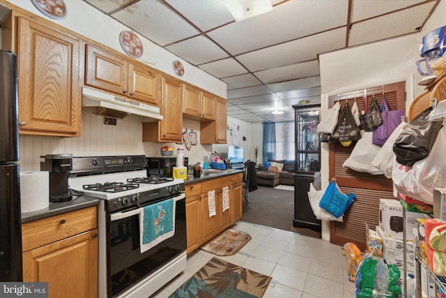 3449 Hartville St, Philadelphia, PA 19134 - kitchen with a paneled ceiling, dark countertops, gas stove, light tile patterned floors, and under cabinet range hood