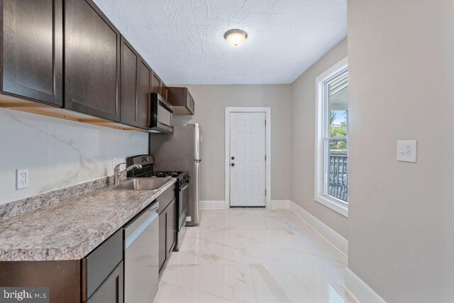 626 Denison St, Baltimore, MD 21229 - kitchen with dark brown cabinets, a textured ceiling, marble finish floor, stainless steel appliances, and baseboards