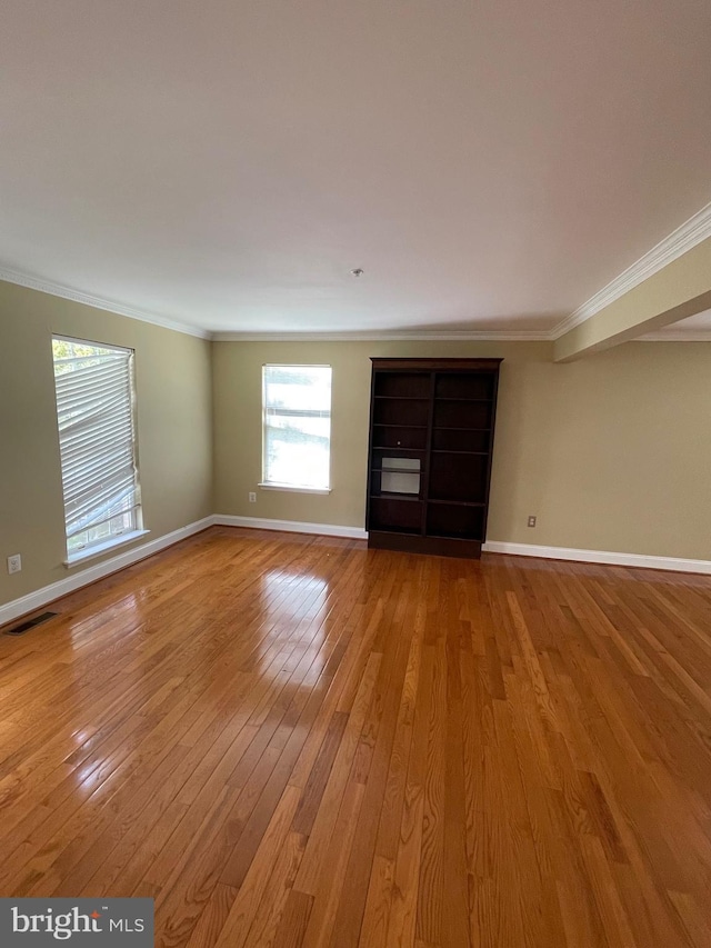 unfurnished living room with light wood-style floors, baseboards, crown molding, and visible vents