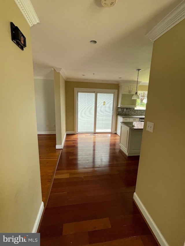 hall featuring crown molding, baseboards, and dark wood-type flooring