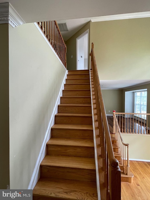stairs featuring baseboards, wood finished floors, and visible vents