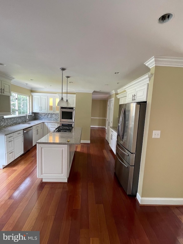 kitchen with appliances with stainless steel finishes, tasteful backsplash, a center island, baseboards, and white cabinetry