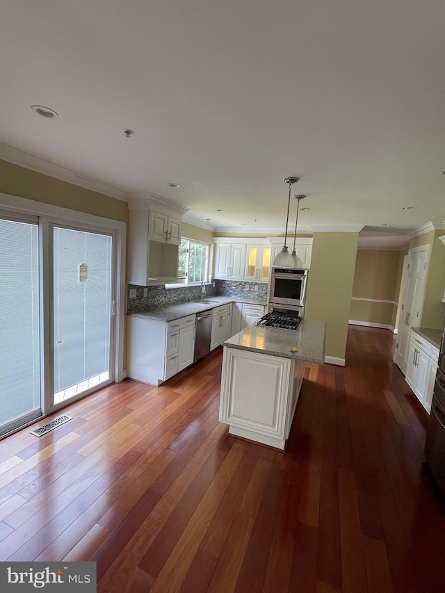 kitchen with white cabinetry, tasteful backsplash, a sink, dark wood finished floors, and stainless steel appliances