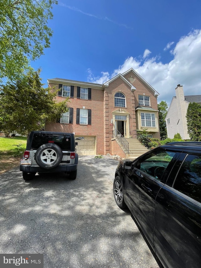 view of front of home with a garage, aphalt driveway, and brick siding