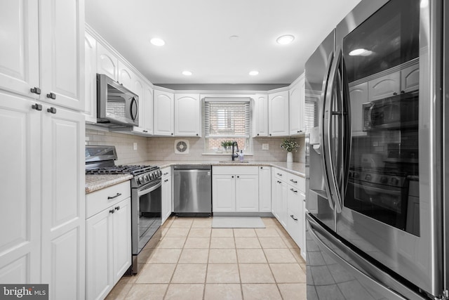 kitchen featuring a sink, appliances with stainless steel finishes, light tile patterned floors, and tasteful backsplash