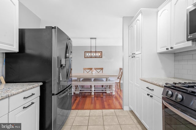kitchen featuring decorative backsplash, white cabinets, and stainless steel appliances