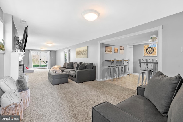 carpeted living area with baseboards and visible vents