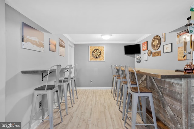 bar featuring baseboards, a dry bar, ornamental molding, and wood finished floors