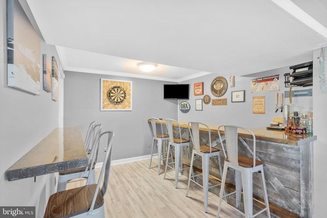bar featuring indoor wet bar, crown molding, baseboards, and wood finished floors