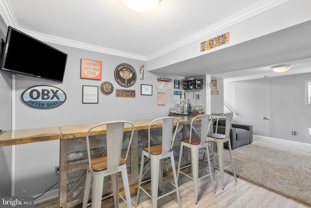 bar featuring crown molding, baseboards, wet bar, and wood finished floors