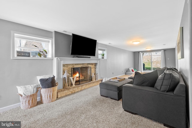 carpeted living room with baseboards, a fireplace, and visible vents