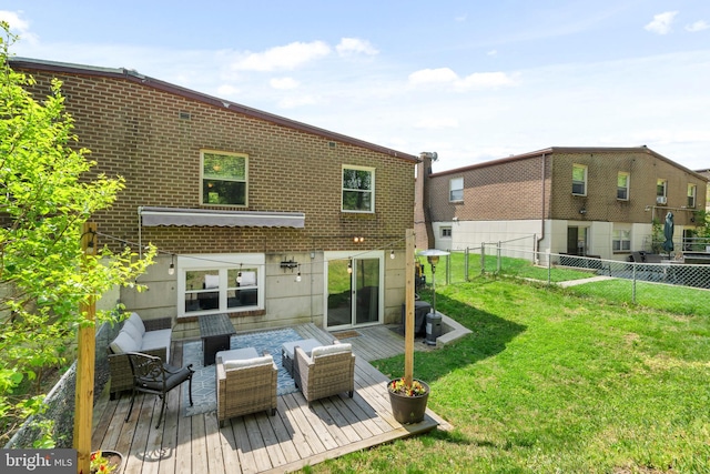 back of house with a lawn, brick siding, a wooden deck, and a fenced backyard