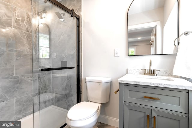 full bathroom with toilet, baseboards, a shower stall, and vanity