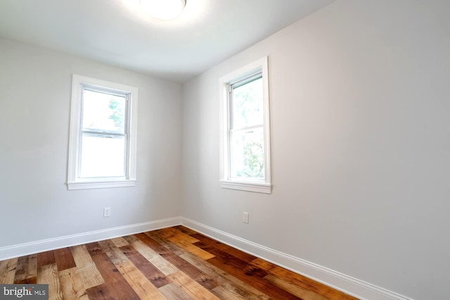 spare room featuring baseboards and wood finished floors
