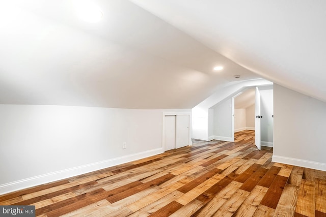 additional living space featuring baseboards, lofted ceiling, and light wood-type flooring