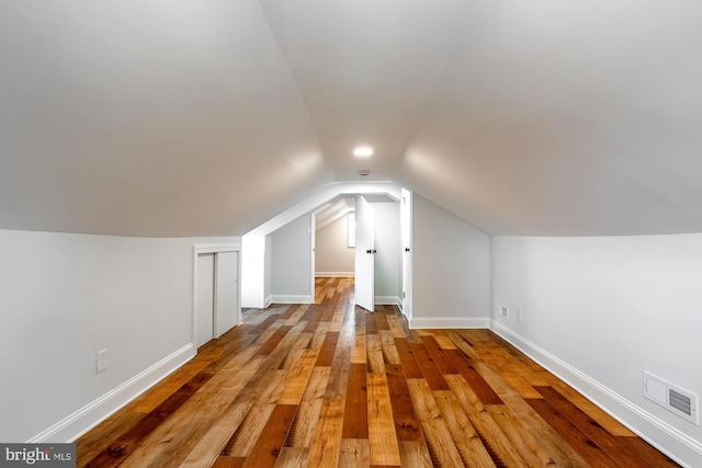 additional living space with visible vents, baseboards, vaulted ceiling, and hardwood / wood-style floors