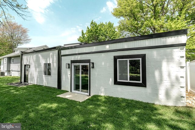 back of property featuring concrete block siding, a yard, and cooling unit