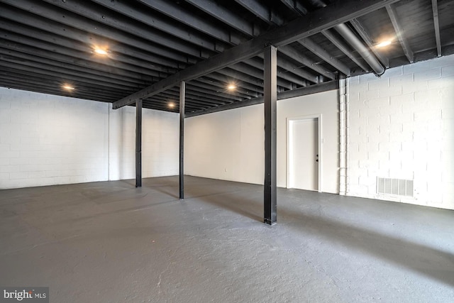 unfinished basement with concrete block wall and visible vents