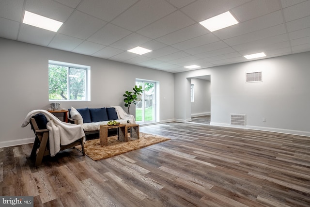 living room featuring visible vents, baseboards, a drop ceiling, and wood finished floors