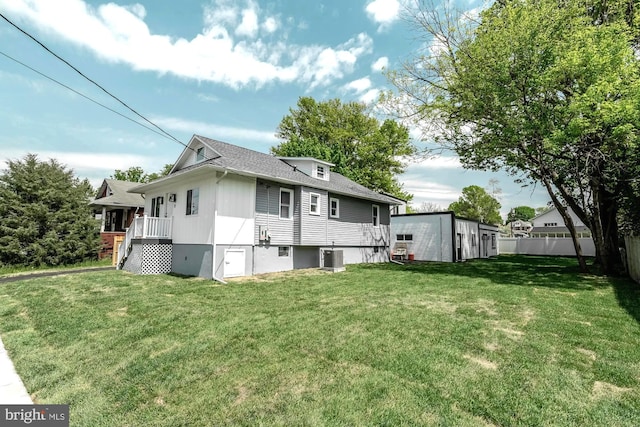 back of house featuring central AC, fence, a wooden deck, a shingled roof, and a yard