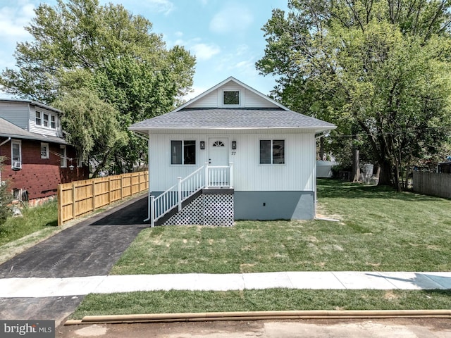 bungalow with a shingled roof, a front lawn, and fence
