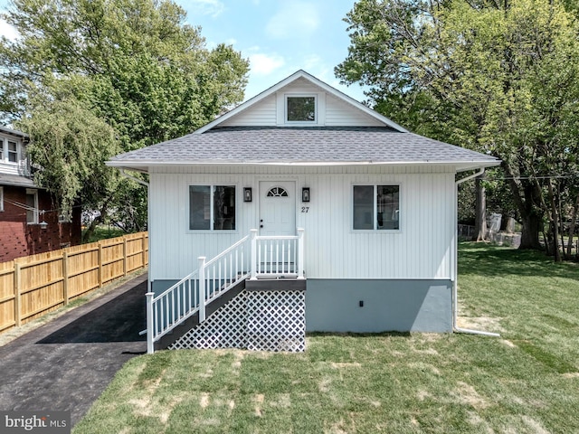 bungalow with fence, a shingled roof, and a front lawn