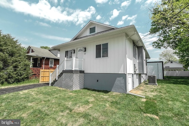 view of front of home featuring fence, central AC unit, and a front yard