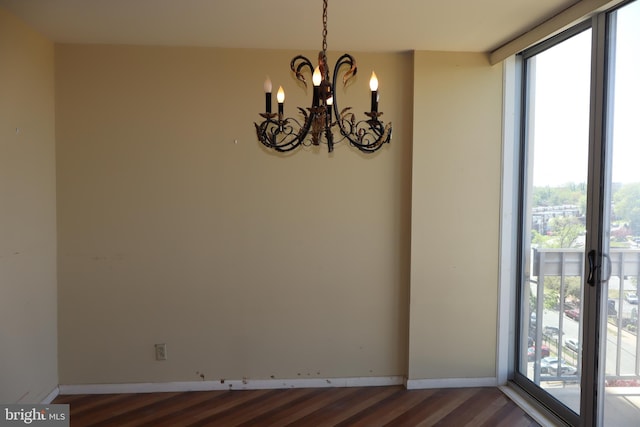 unfurnished dining area with an inviting chandelier, dark wood-style flooring, baseboards, and a wealth of natural light