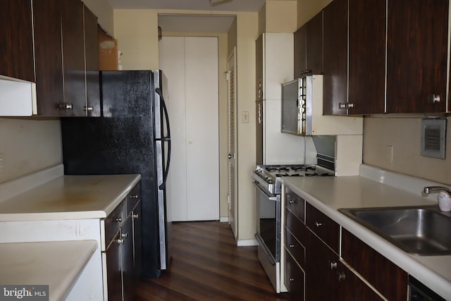 kitchen with dark wood finished floors, dark brown cabinets, gas stove, light countertops, and a sink