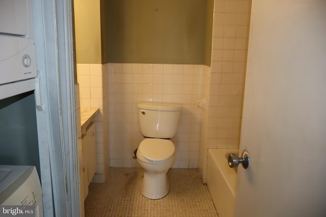 full bath featuring a washtub, tile walls, tile patterned floors, vanity, and toilet