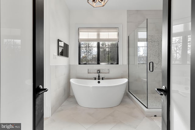full bath with tile walls, a soaking tub, a stall shower, and marble finish floor