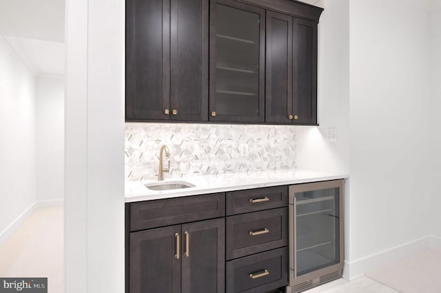 bar featuring a sink, beverage cooler, baseboards, decorative backsplash, and indoor bar