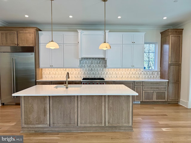 kitchen with decorative backsplash, ornamental molding, light countertops, stainless steel built in fridge, and a sink