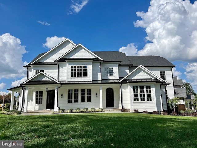 traditional home with a standing seam roof, covered porch, metal roof, and a front lawn