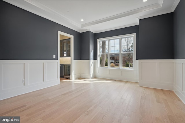 unfurnished room with ornamental molding, light wood-style flooring, and a decorative wall