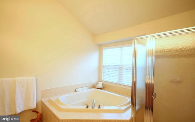 full bath with vaulted ceiling, a bath, and a stall shower