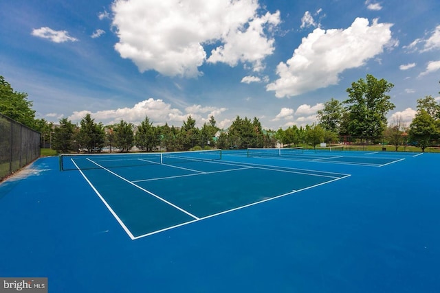 view of tennis court featuring community basketball court and fence