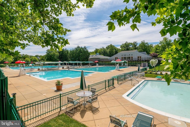 community pool featuring fence and a patio area
