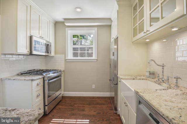 9709 W Bexhill Dr, Kensington, MD 20895 - kitchen featuring glass insert cabinets, dark wood-style floors, tasteful backsplash, light stone counters, and stainless steel appliances