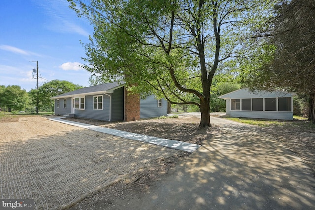 ranch-style home featuring a sunroom and dirt driveway