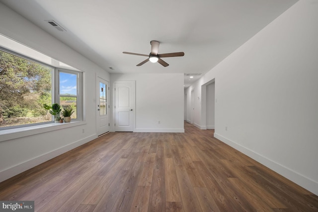 spare room featuring visible vents, a ceiling fan, baseboards, and wood finished floors