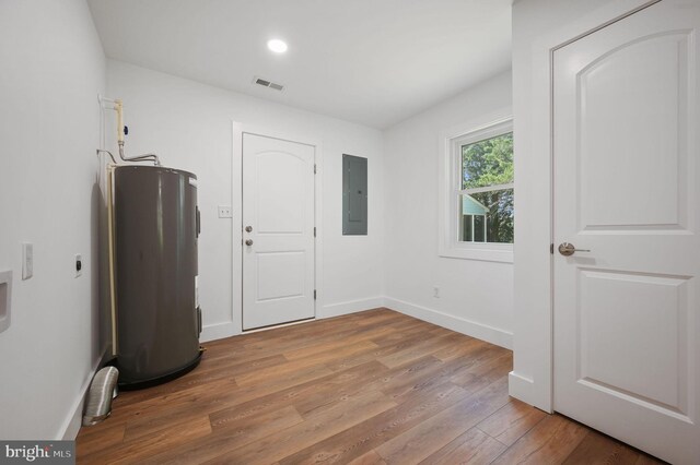 interior space featuring visible vents, wood finished floors, baseboards, electric panel, and electric water heater