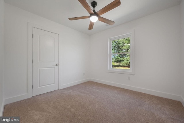 empty room featuring baseboards, ceiling fan, and carpet