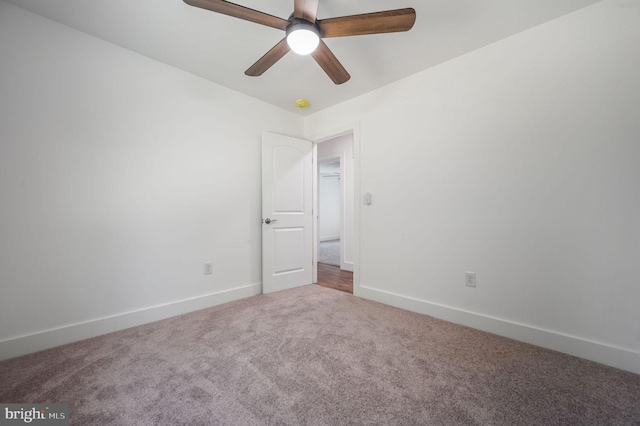 carpeted spare room featuring baseboards and ceiling fan