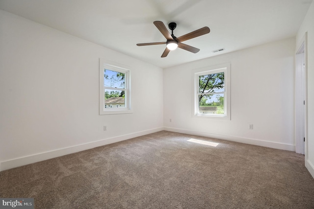 empty room with a healthy amount of sunlight, baseboards, carpet flooring, and visible vents