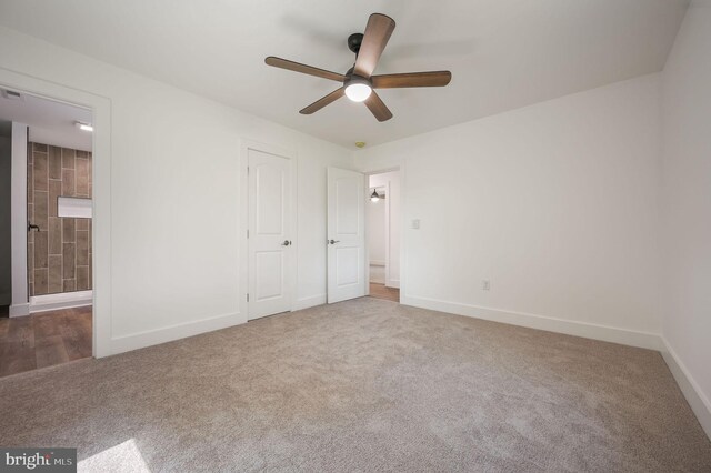 unfurnished bedroom with carpet floors, baseboards, ceiling fan, and ensuite bath